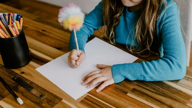 Una mano di bambino che scrive su un quaderno: la disgrafia rende il gesto della scrittura faticoso e poco fluente