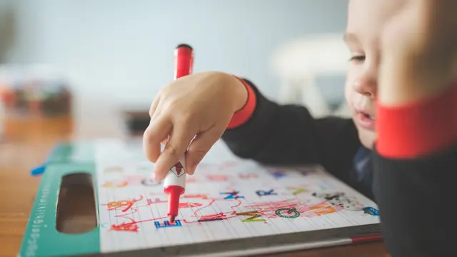 Un bambino concentrato che scrive su un quaderno: la disortografia si vede negli errori ortografici che restano nonostante lo studio delle regole