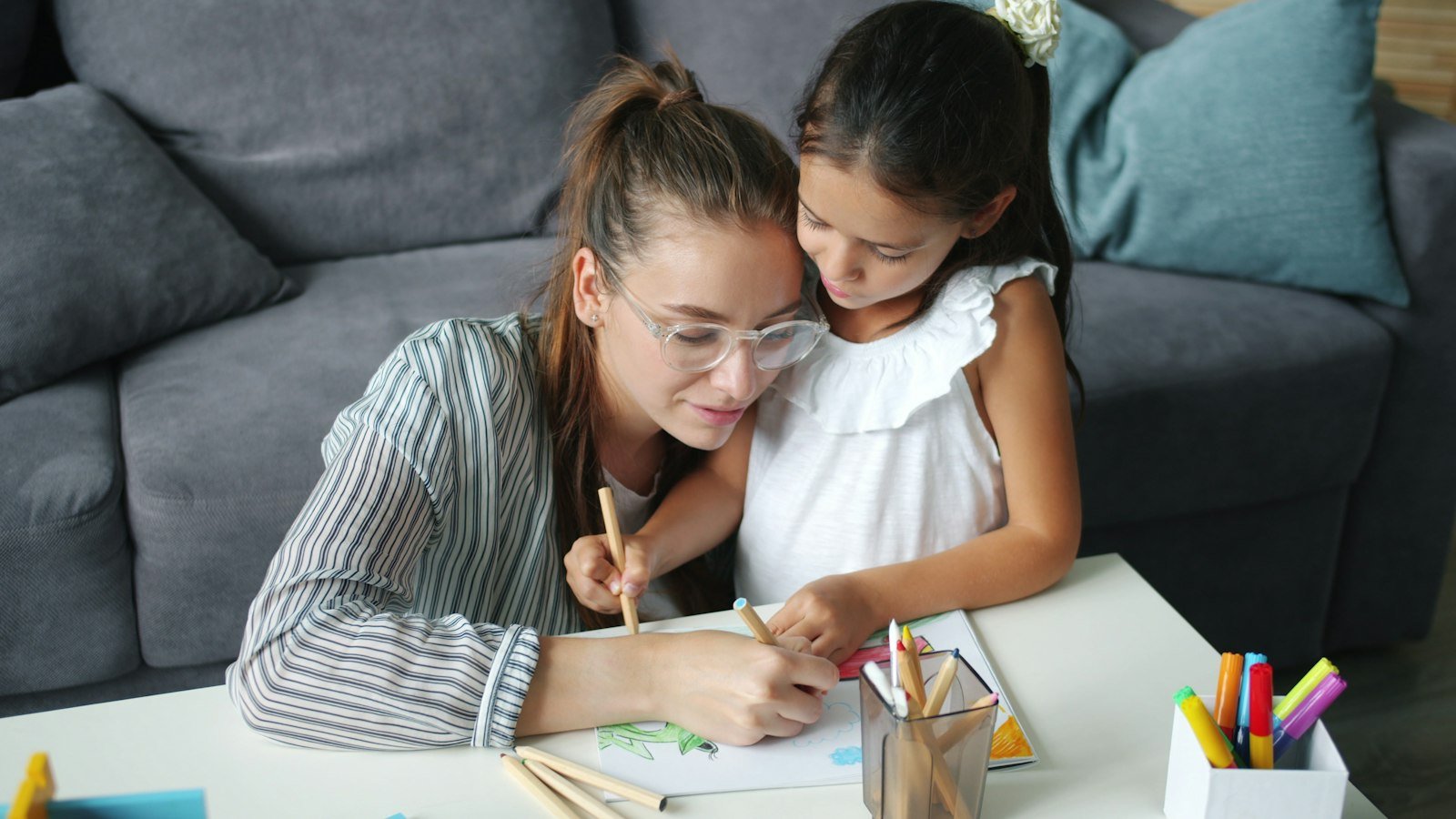 Una madre e una bambina disegnano insieme al tavolo del soggiorno: capire il profilo di un bambino plusdotato serve prima di tutto a chi vive con lui ogni giorno