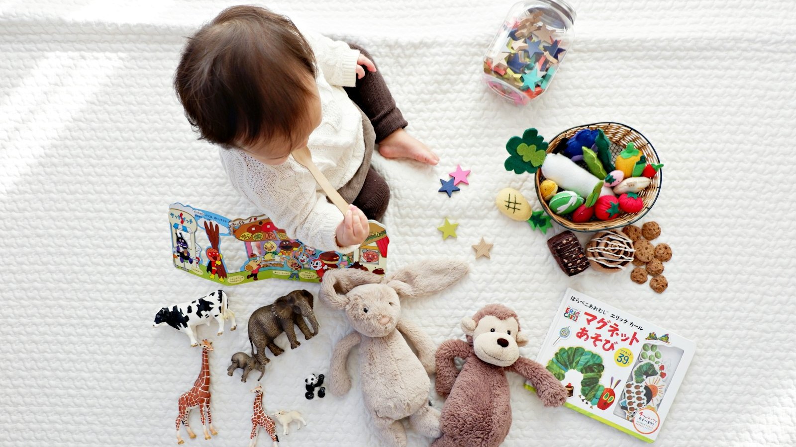 Un bambino piccolo gioca da solo, seduto tra giochi disposti in ordine: alcuni sintomi di autismo nei bambini si notano proprio osservando il gioco